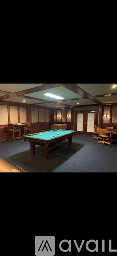 A pool table in a room with wooden walls and a high ceiling.