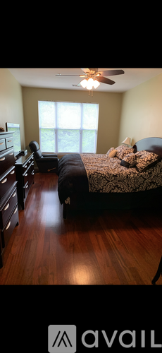 A bedroom with a bed, dresser, and ceiling fan.