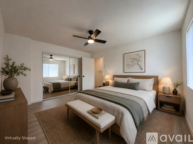 A bedroom with a large bed, a ceiling fan, and a mirror on the wall.