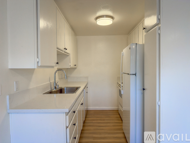 A kitchen with white cabinets and a white fridge.