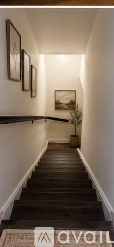 A hallway with a staircase and pictures on the wall.