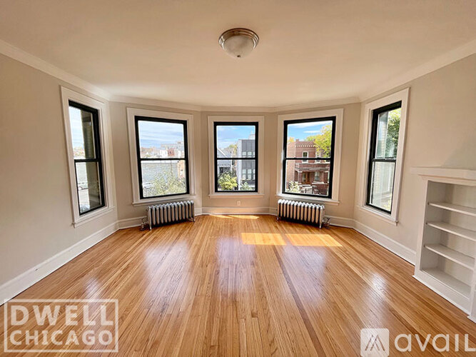 A spacious room with wooden floors and large windows.