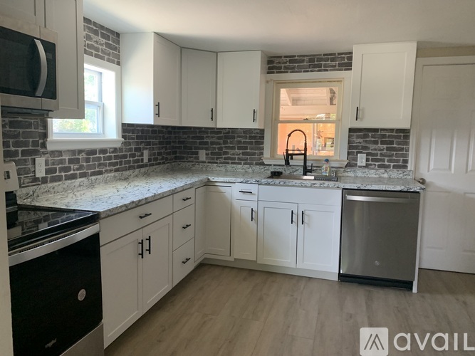A kitchen with white cabinets and a brick backsplash.