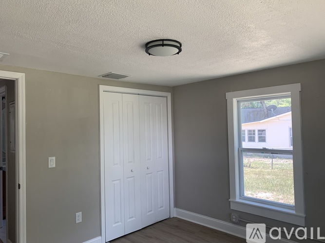 A room with a white door and a window showing a view of a house.