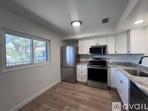 A kitchen with white cabinets and a stainless steel refrigerator.