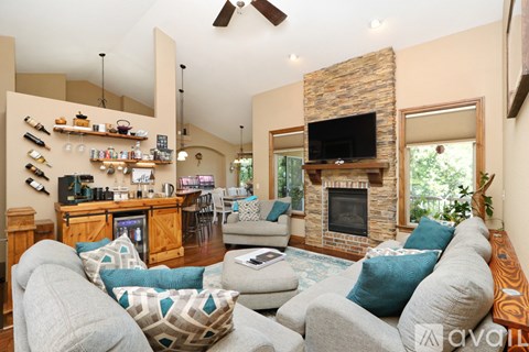 A living room with a grey couch and a stone fireplace.