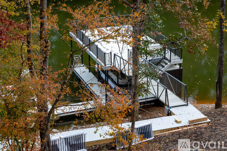 A deck with a staircase and railings overlooking a body of water surrounded by trees.