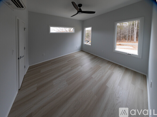 A spacious room with wooden flooring and a ceiling fan.