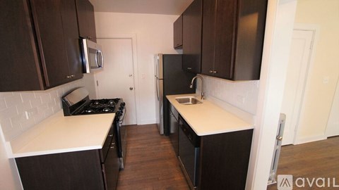 A kitchen with dark brown cabinets and white countertops.