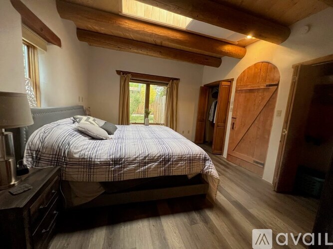 A bedroom with a bed, nightstand, and wooden floors.
