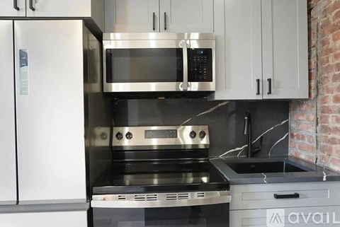 A modern kitchen with a stainless steel refrigerator, microwave, oven, and sink.
