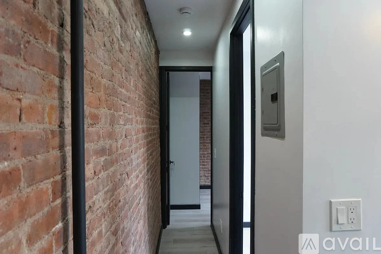 A hallway with a brick wall on the left and a white wall on the right.