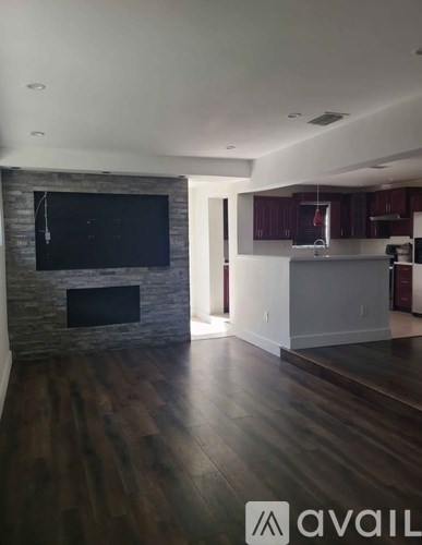 A modern living room with a stone fireplace and a television above it.