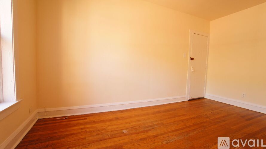 A room with wooden floors and a door is available for rent.
