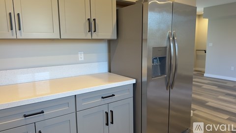 A kitchen with a stainless steel refrigerator and cabinets.
