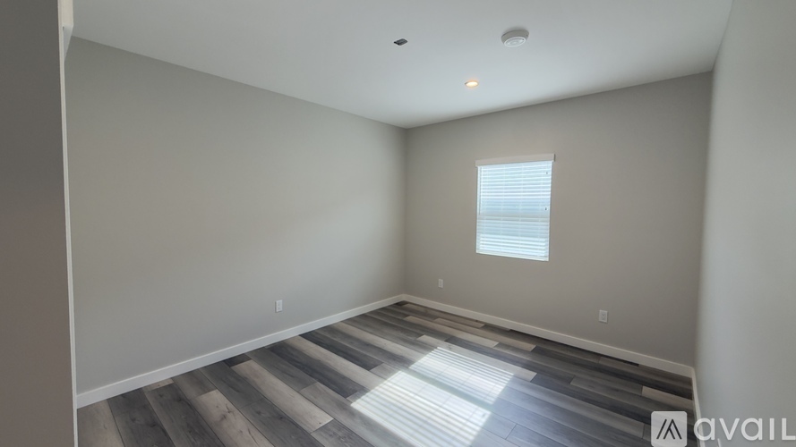 A room with wooden flooring and a window with blinds.
