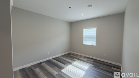 A room with wooden flooring and a window with blinds.