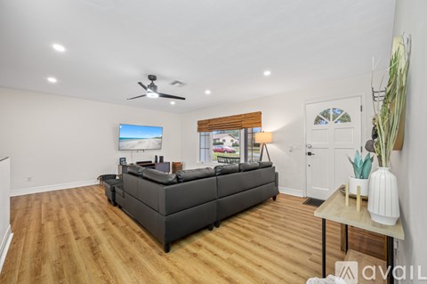 A spacious living room with a grey sofa and wooden flooring.