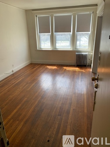 A room with wooden flooring and a window with blinds.