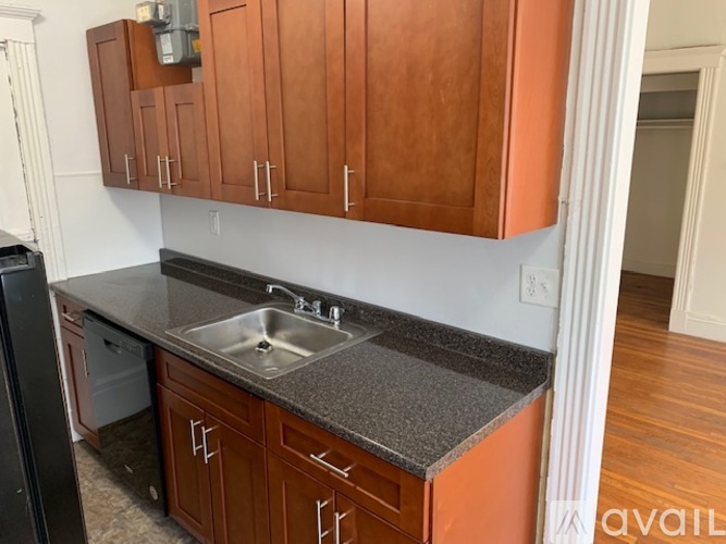 A kitchen with brown cabinets and a black fridge.