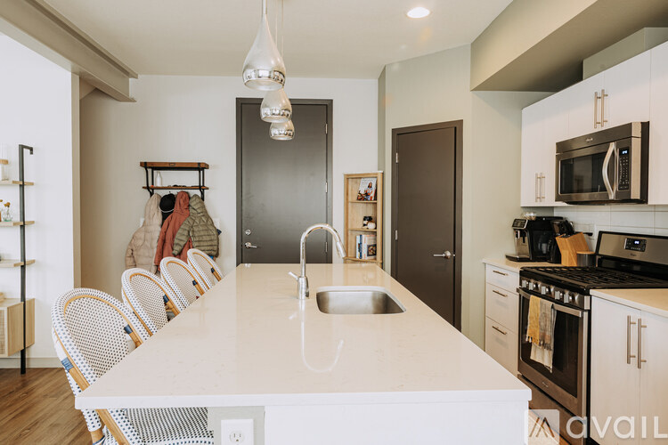 A kitchen with a table and chairs in the foreground and a person standing in the background.