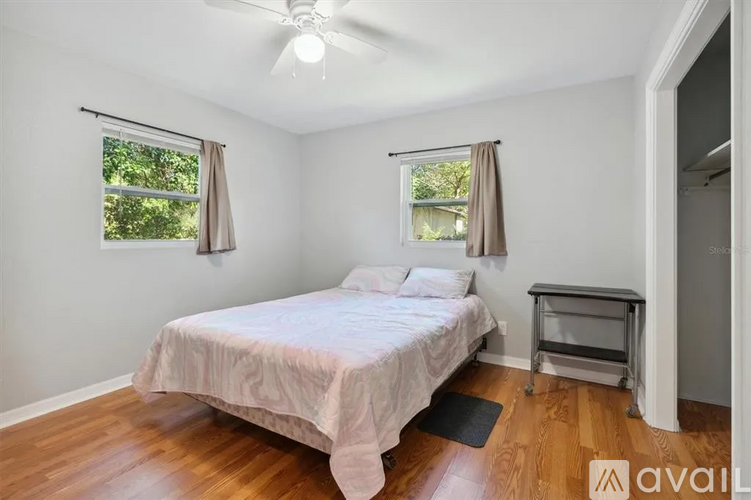 A bedroom with a bed, a ceiling fan, and a window with curtains.