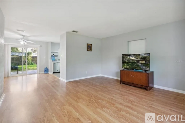 A spacious room with wooden flooring and a television on a wooden stand.