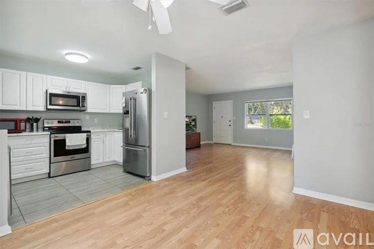 A kitchen with white cabinets and a wooden floor.