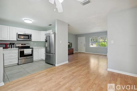 A kitchen with white cabinets and a wooden floor.