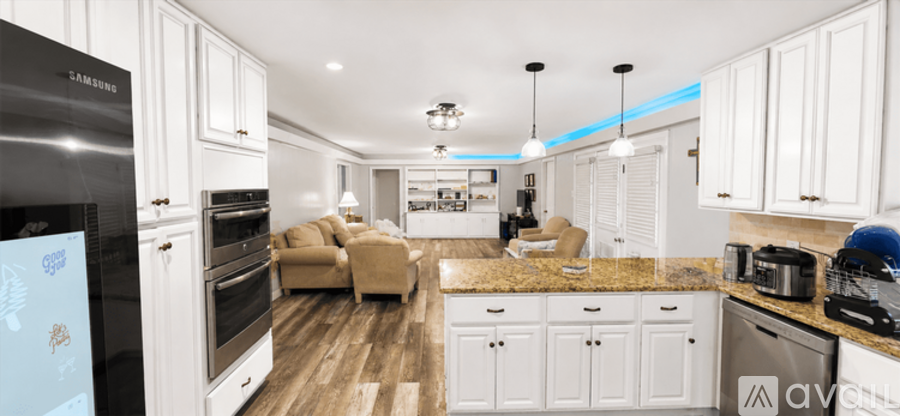 A modern kitchen with white cabinets and a wooden floor.