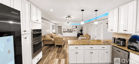 A modern kitchen with white cabinets and a wooden floor.
