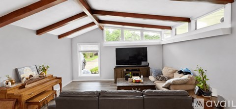 A living room with a brown couch and a wooden desk.