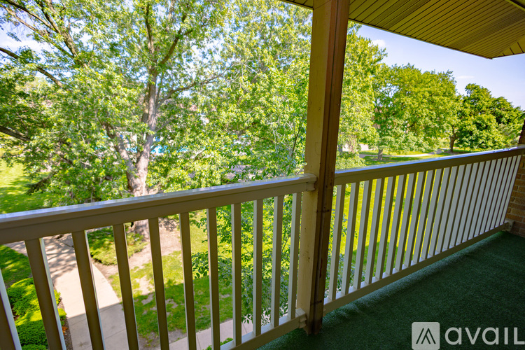 A balcony with a view of a tree and a pathway.