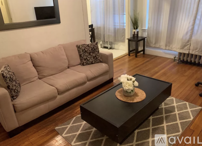 A living room with a beige couch, a coffee table, and a grey rug.