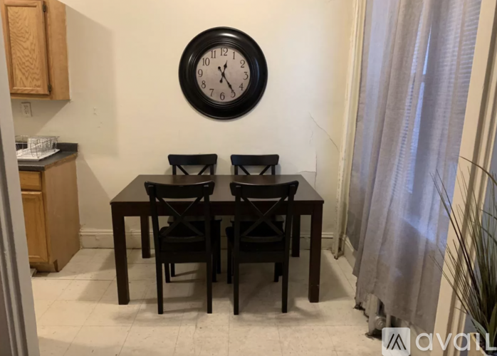 A black and white clock hangs on a wall above a table with two chairs.