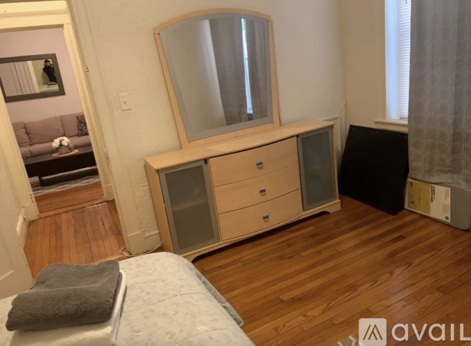 A bedroom with a bed, a dresser with a mirror, and a window with curtains.