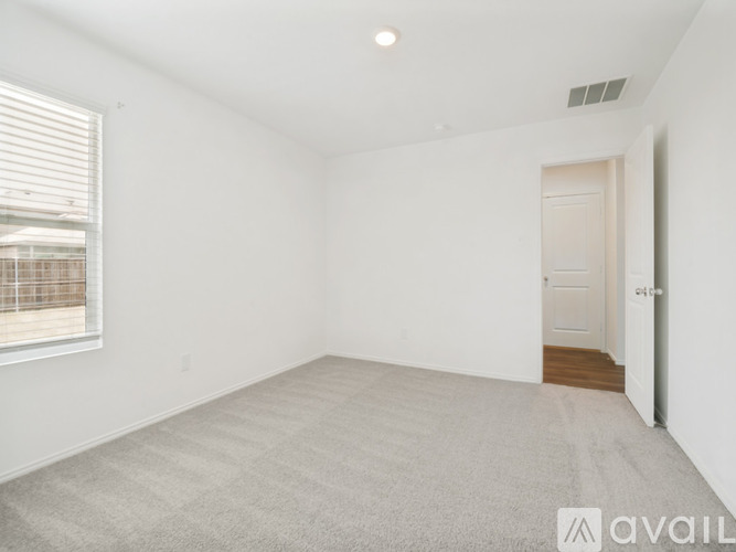 A spacious room with a carpeted floor and a door on the right side.