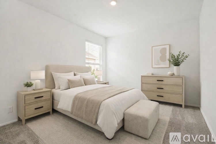 A well-lit bedroom with a large bed, nightstand, and a small plant on the side table.