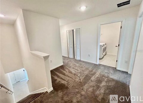 A spacious room with a carpeted floor and white walls.