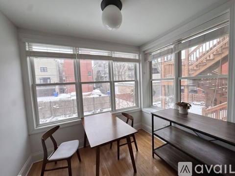 A room with a table and chairs in front of a window.