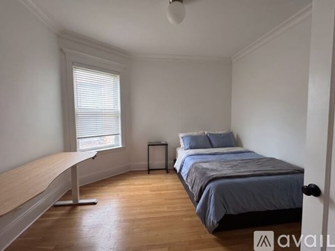 A bedroom with a bed, nightstand, and window.
