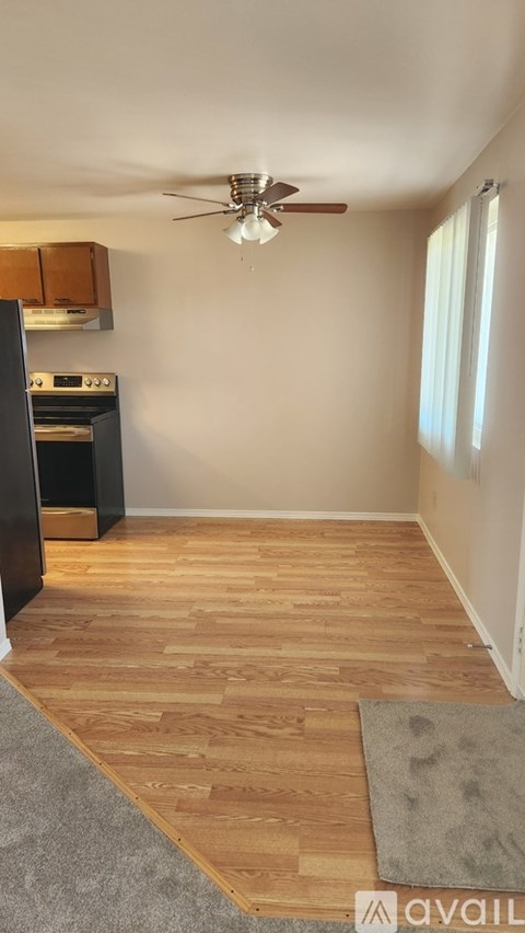 A kitchen area with wooden flooring and a ceiling fan.