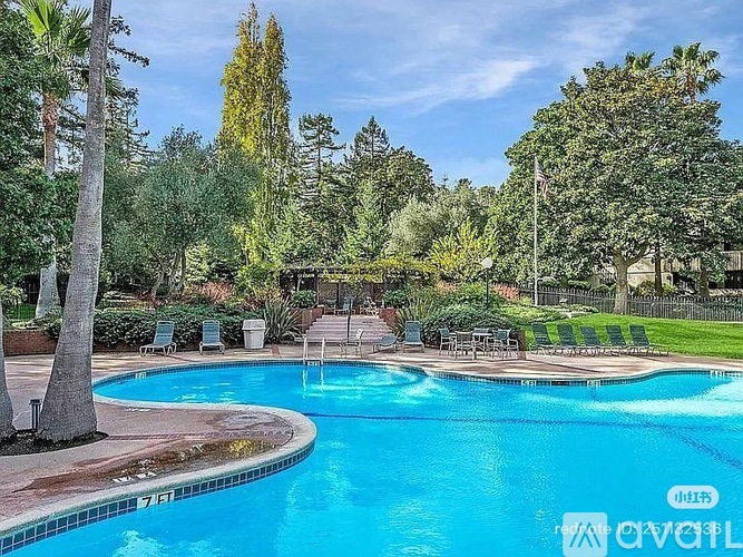 A pool surrounded by trees and lawn chairs.