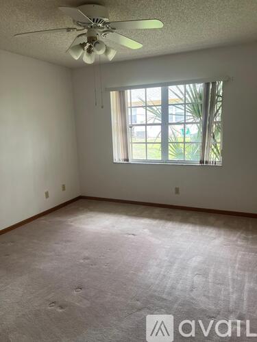 A room with a ceiling fan and a window with a view of a building outside.