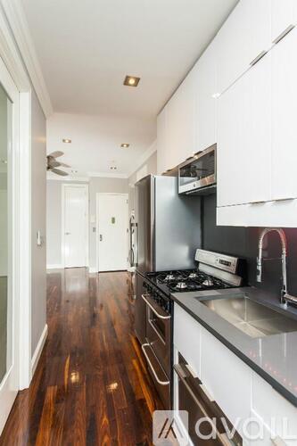 A modern kitchen with a dark wood floor and white cabinets.