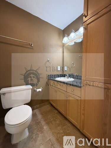 A bathroom with a toilet, sink, and wooden cabinets.