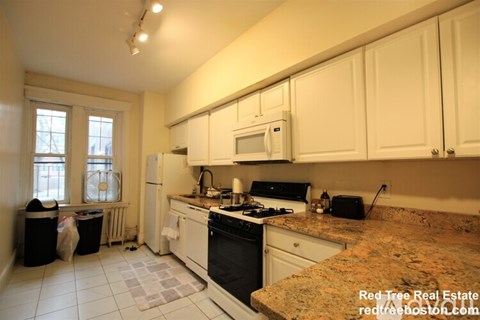 A kitchen with white cabinets and a granite counter top.