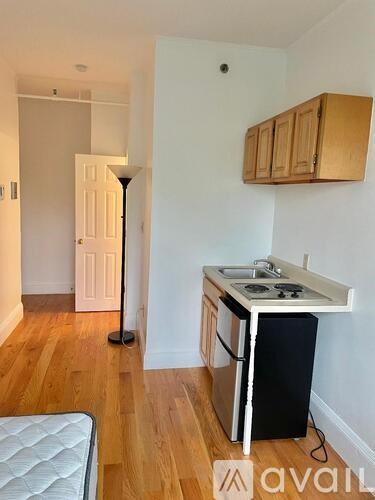 A small kitchen with wooden cabinets and a black fridge.