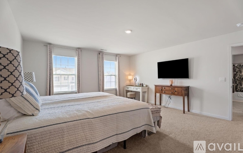 A bedroom with a large bed, a desk, and a television.