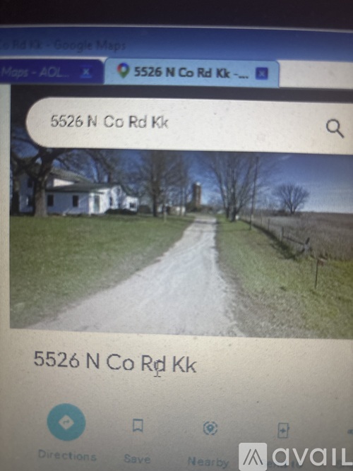 A road with a white house on the left and a fence on the right.